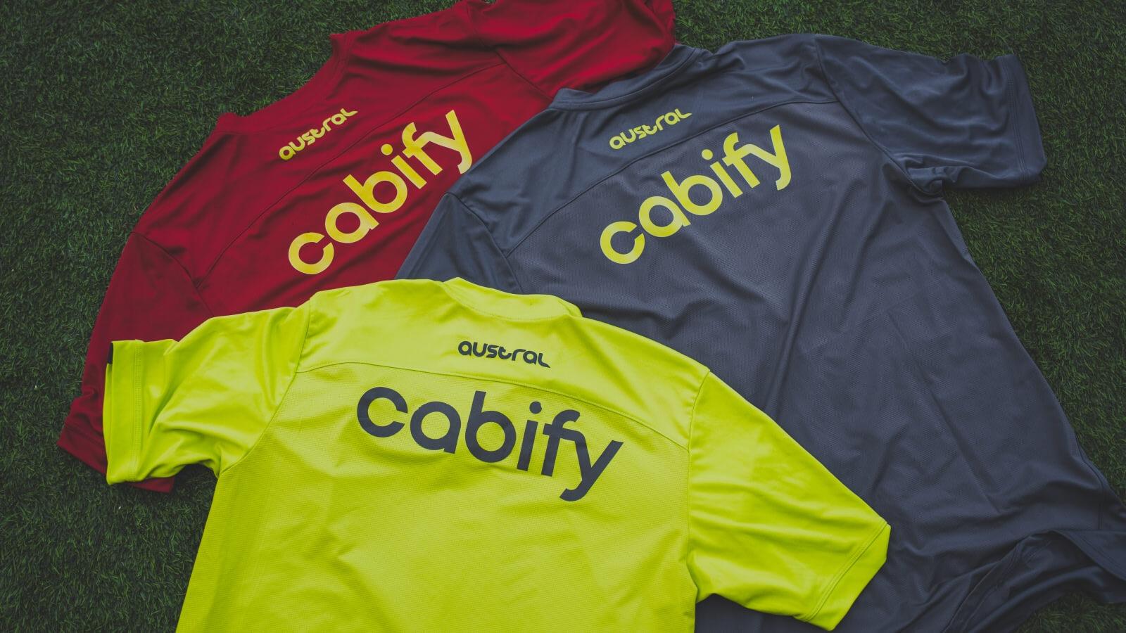 Varias camisetas de fútbol con el nombre de Cabify sobre césped
